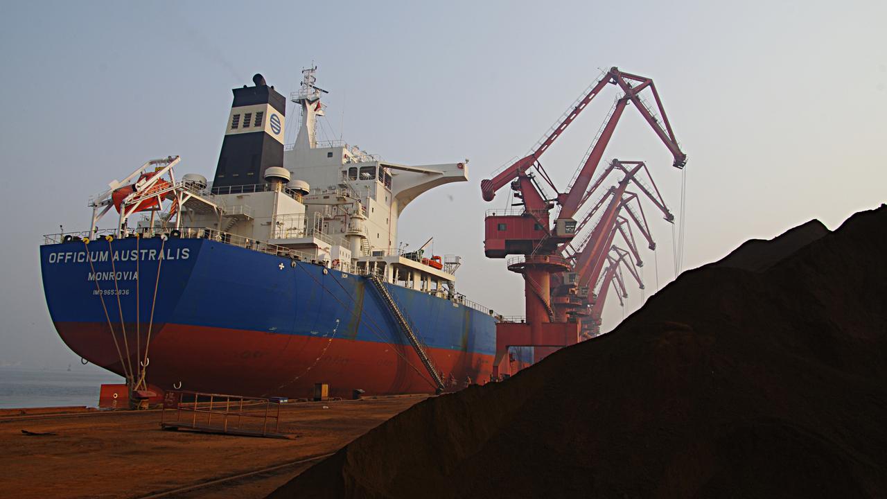 Cranes unload iron ore from a ship at a port in Rizhao, China